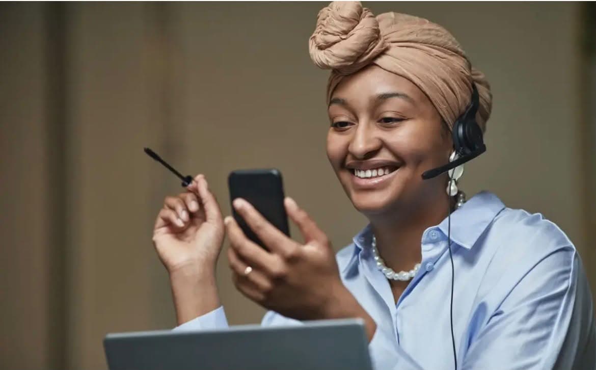 Asesora de Ketal Network sonriendo mientras atiende a una clienta por teléfono y computador.